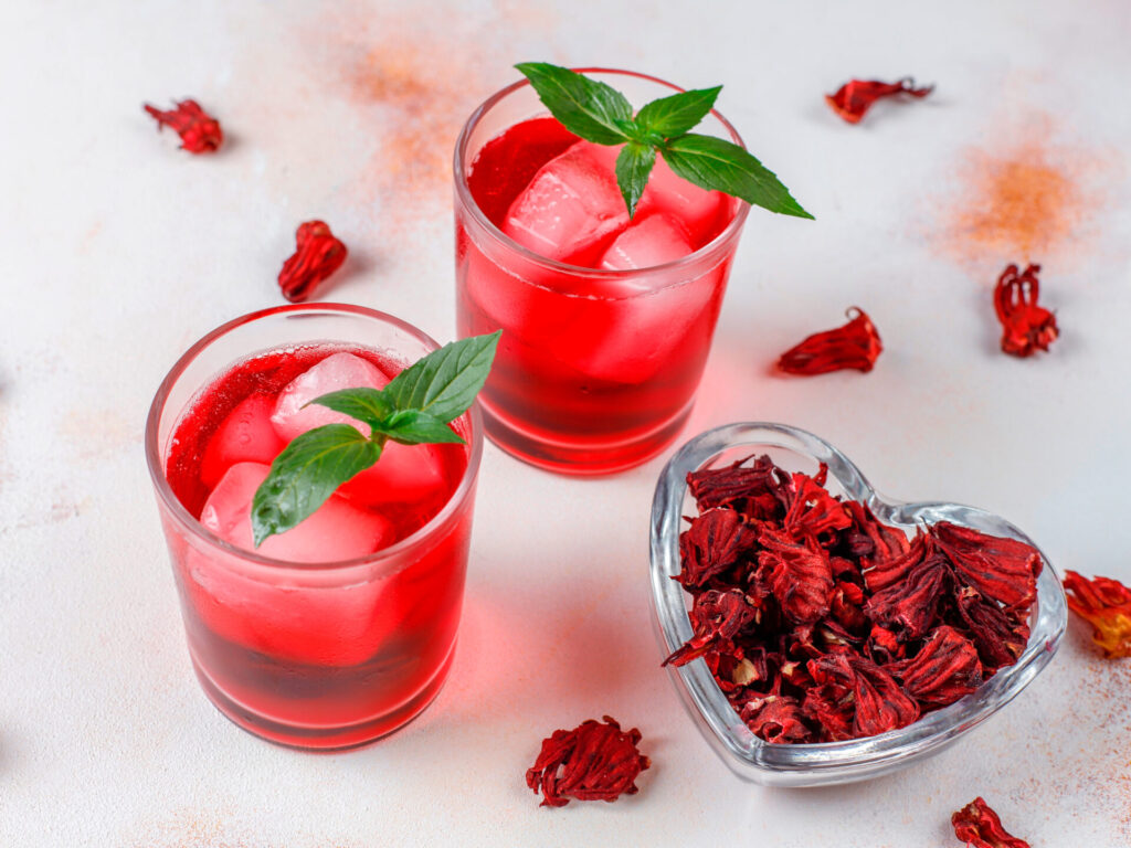 Cold brew hibiscus tea with ice and basil leaves.